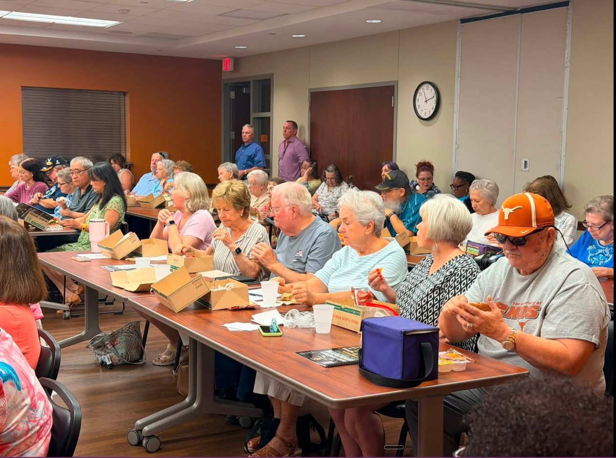Seniors seated at tables during a fraud-prevention workshop.